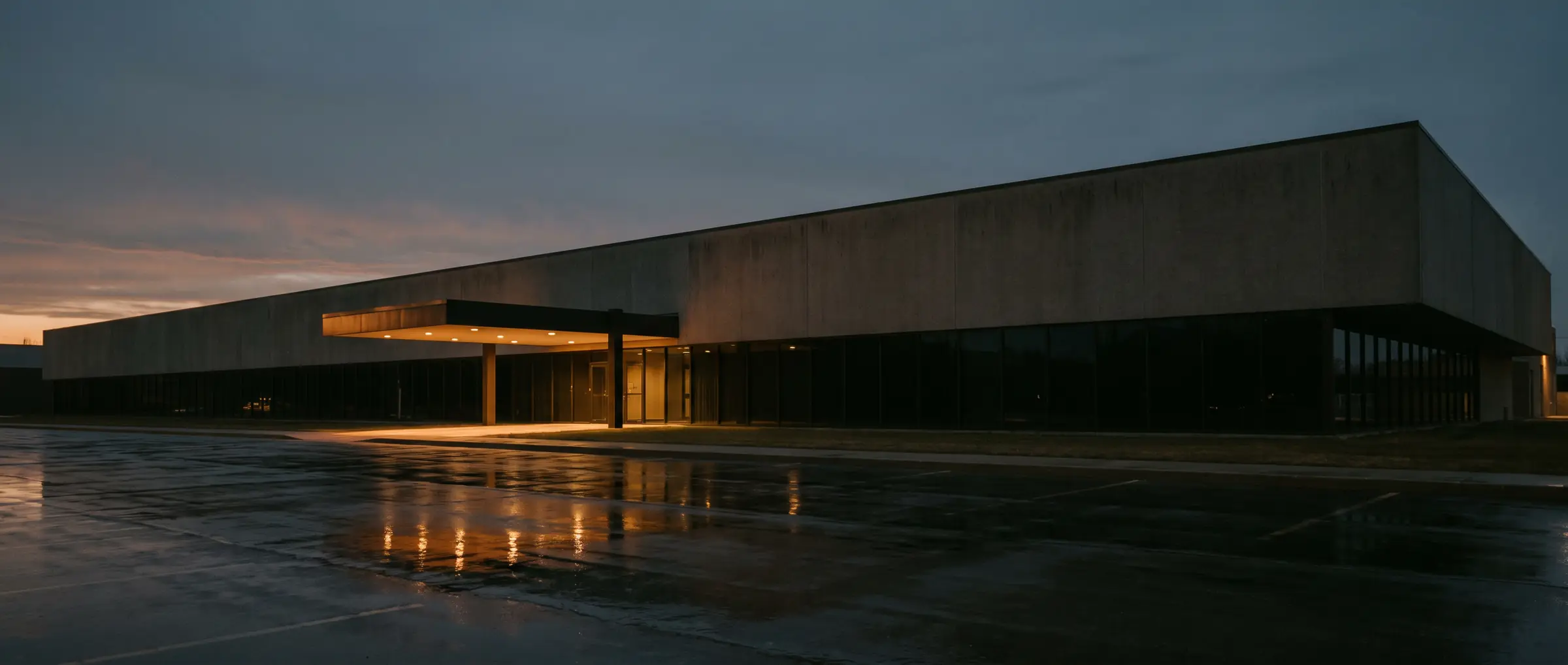 Newly completed single-tenant corporate facility at dusk with a lit cantilevered entry canopy