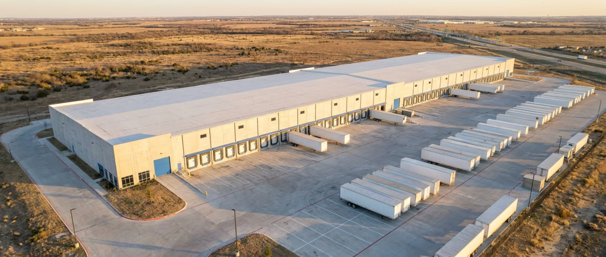 Aerial view of a modern Texas distribution building with a wide truck court at dusk