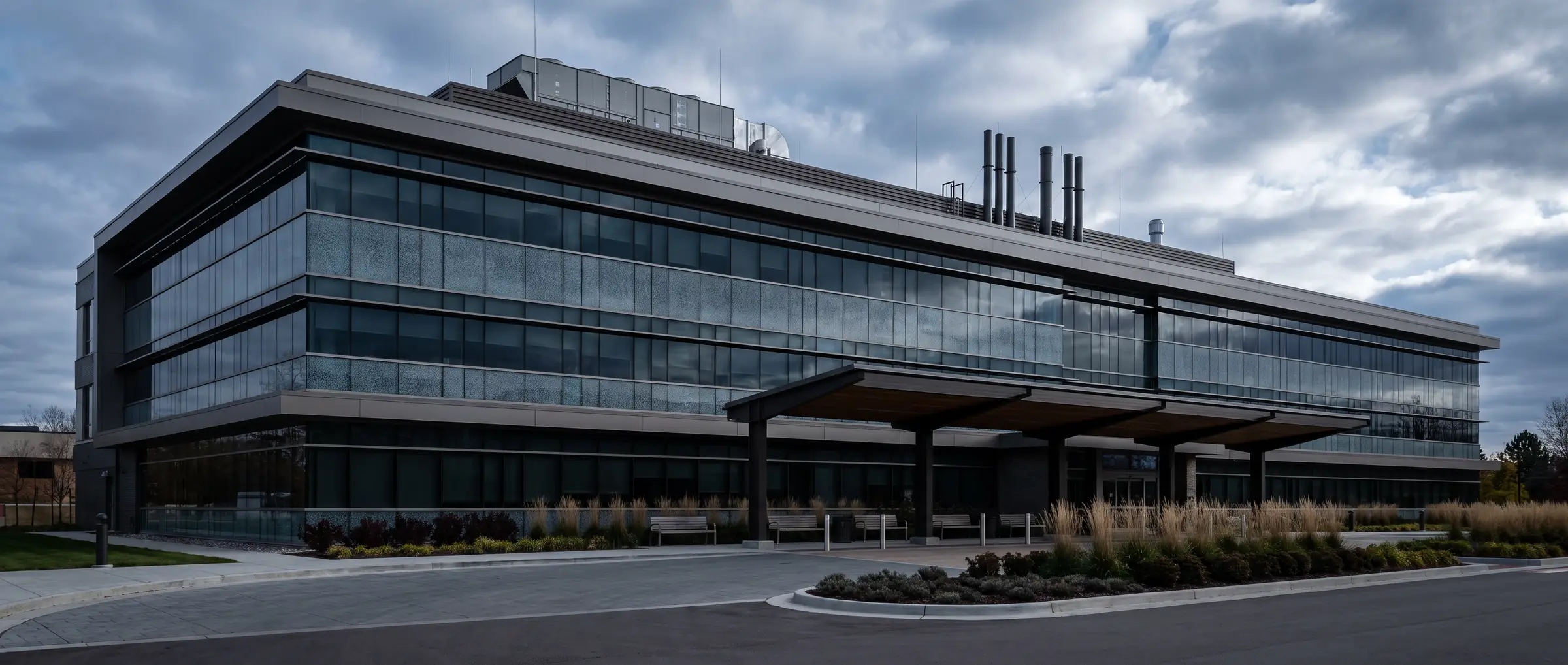 Modern medical office and laboratory building in cool overcast light with ribbon glazing and a covered drop-off
